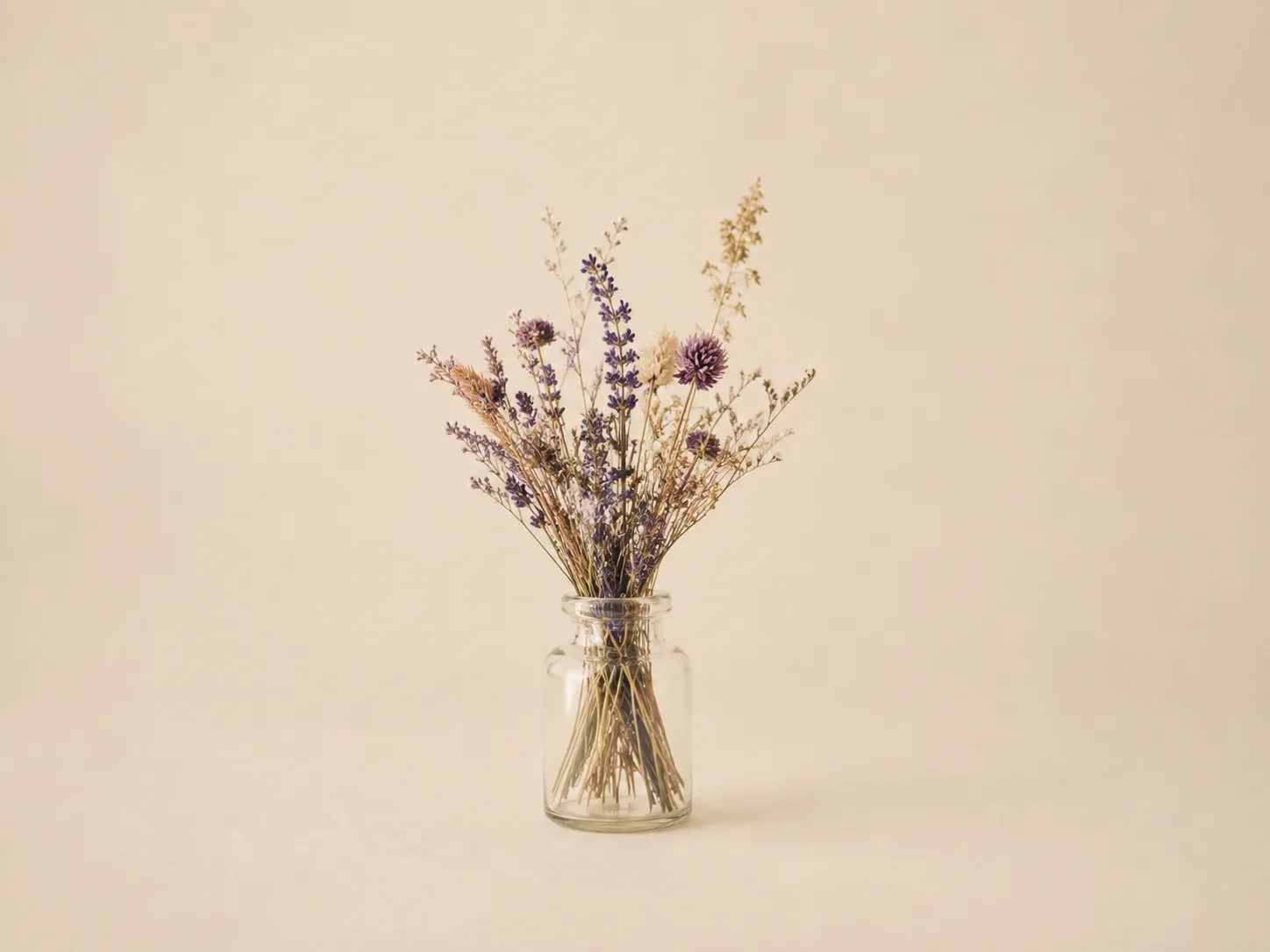 A dried flower in a glass jar on a neutral background